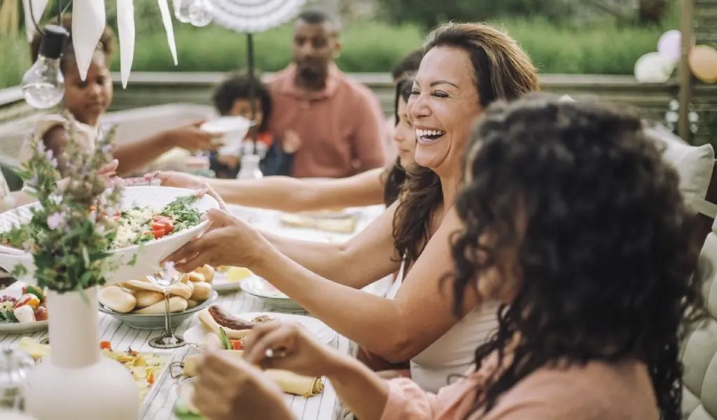 Family enjoying outdoor meal together, sharing food and laughing